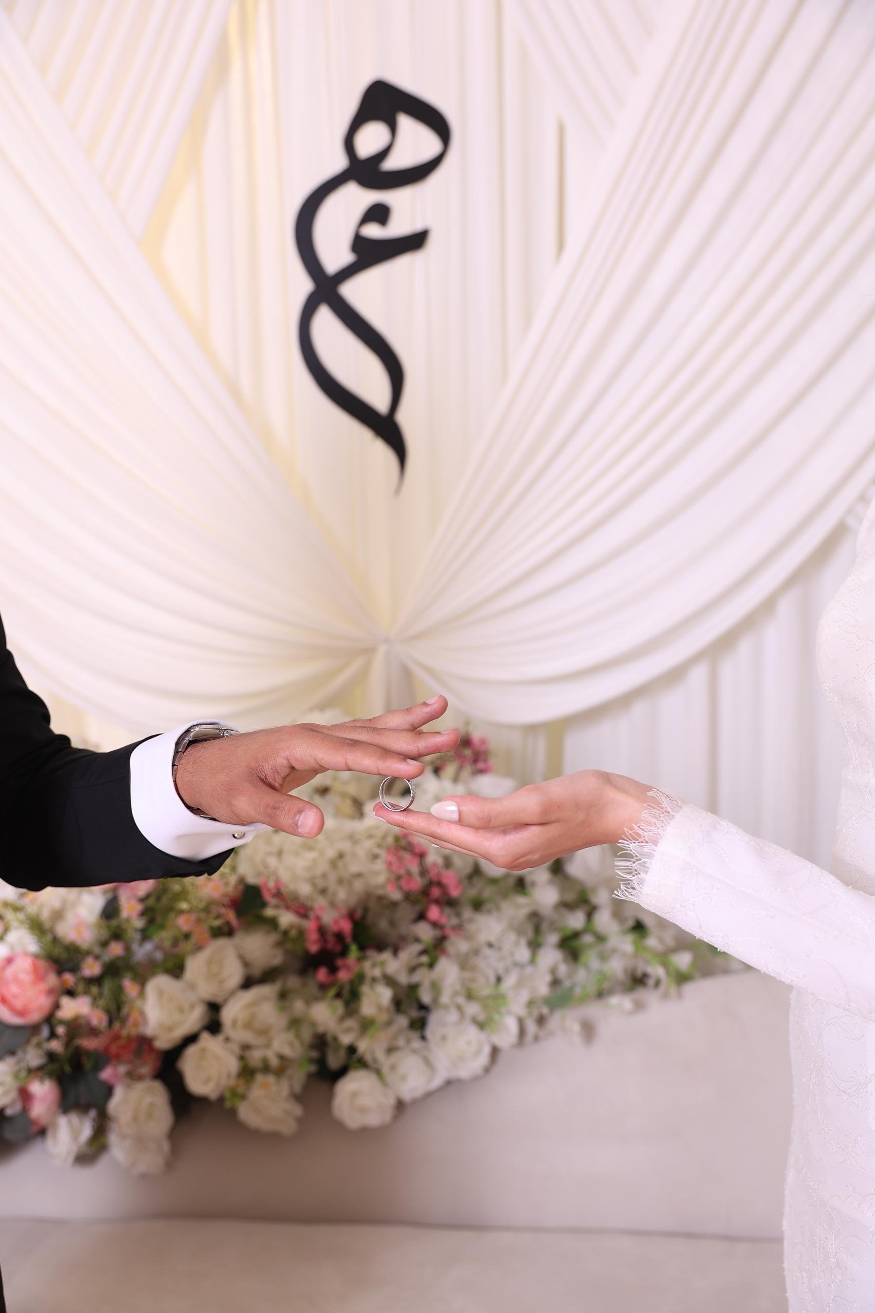 Hajer and Aziz extending their hands toward each other during their ring exchange